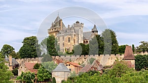 Chateau de Montfort on hill top and villageÃÂ huddled belowÃÂ substantial ramparts of castle with attractive houses in Dordogne